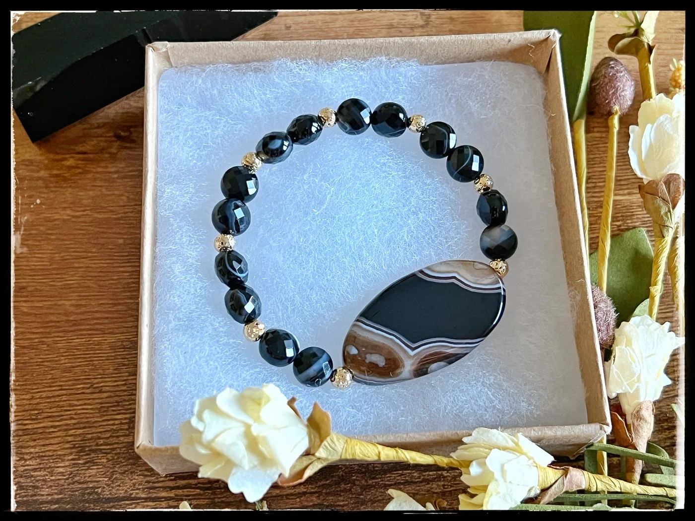 Dark beaded bracelet with a large black and white patterned pendant
