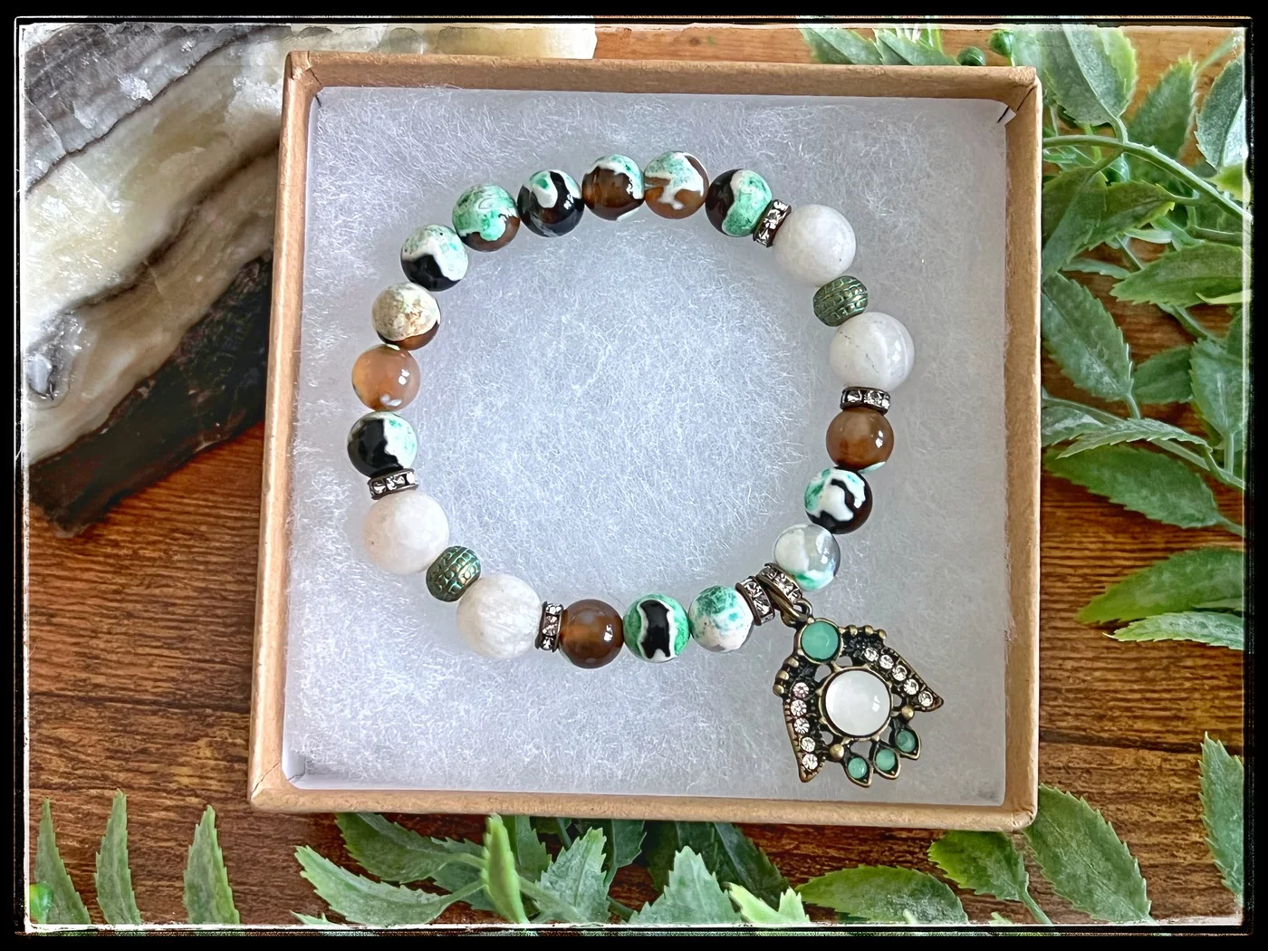 Green, cream, and brown beaded bracelet with an ornate circular charm