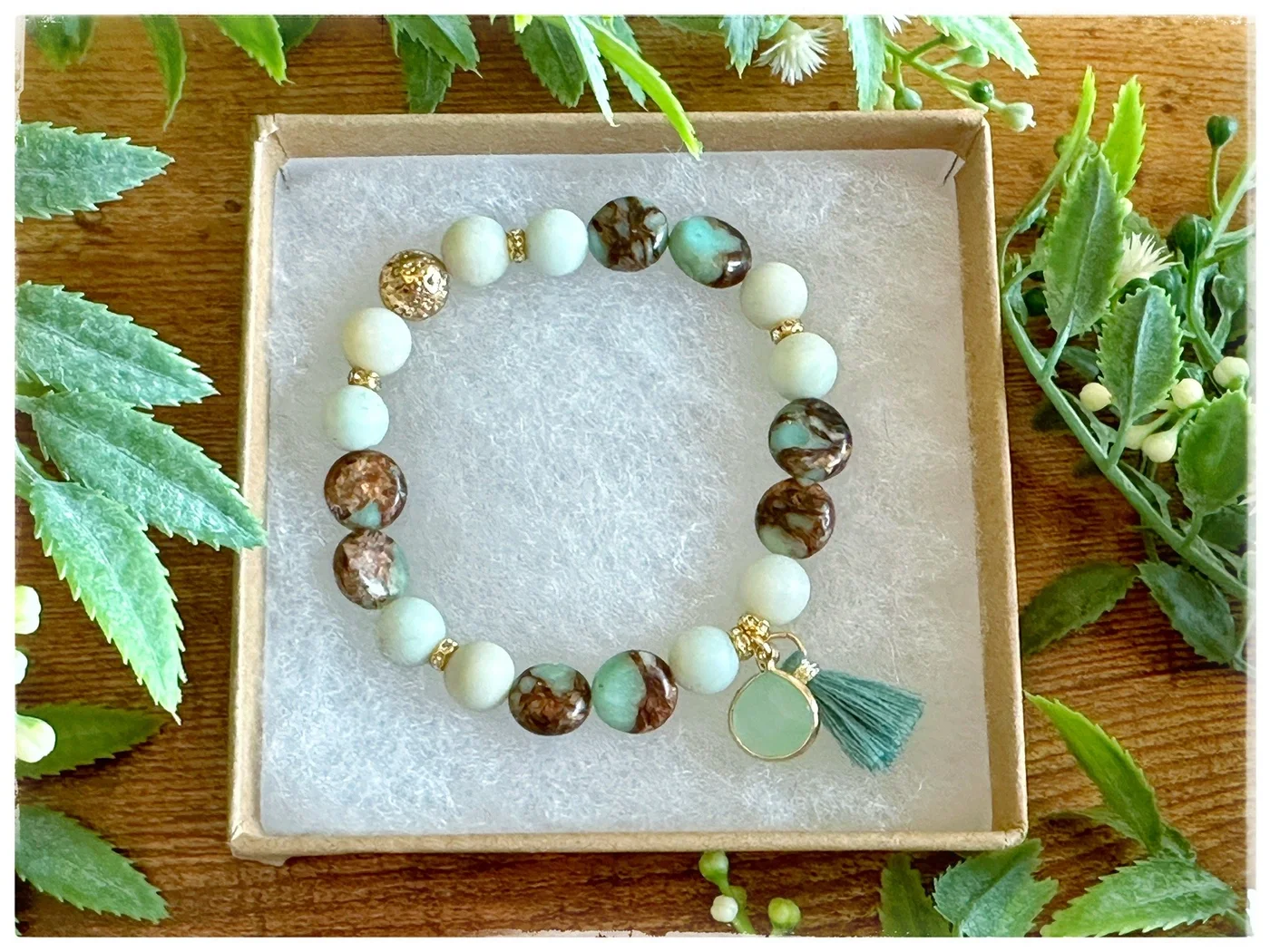 Cream and green beaded bracelet with a green leaf pendant