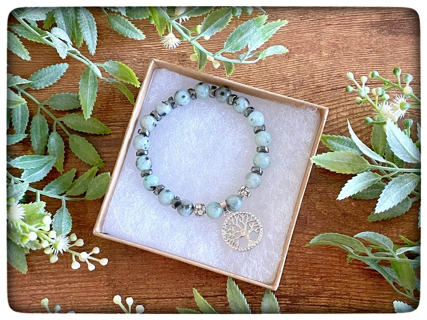 A lavender bracelet with a silver-tone charm, photographed among greenery